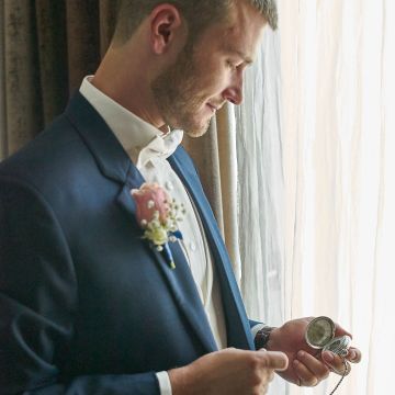 Bräutigam schaut glücklich auf die Taschenuhr