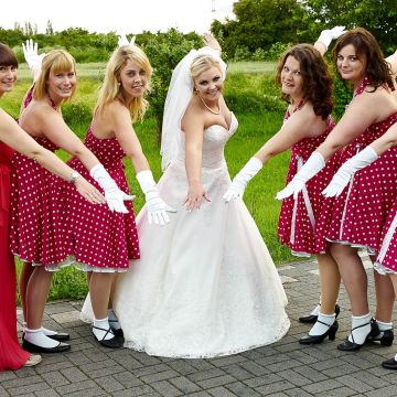Brautjungfern in roten Kleidern mit Dalmatinermuster umringen die Braut