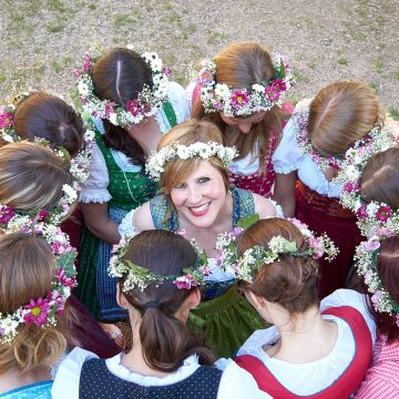 Junggesellinnenabschied im bäuerlichen Outfit mit Blumen im Haar. Braut steht in der Mitte