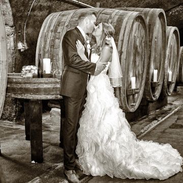 Brautpaar küsst sich in _Weinkeller vor den Weinfässern