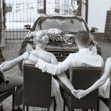 Brautpaar mit Trauzeugen Hand in Hand vorm Hochzeitsauto