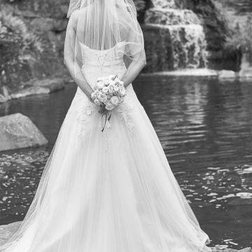Braut von hinten in langem Brautkleid vor einem Wasserfall im japanischen Garten in Kaiserslautern
