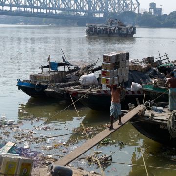 Lastentransport auf dem Kopfe über einen schmalen Steg zu einem Kutter auf dem Ganges