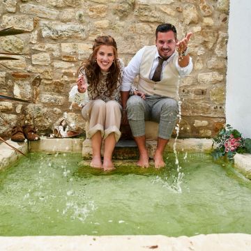 Hochzeitspaar im Springbrunnen spritzt mit Wasser um sich