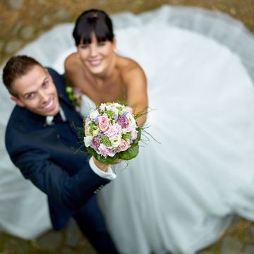 Hochzeitspaar streckt den Brautstrauß in die Kamera