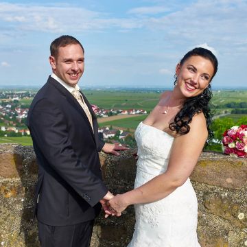 Brautpaar blickt bei strahlendem Sonnenschein von der Burg Neuleiningen auf die Rheinebene