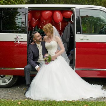 Brautpaar im rot weißen VW Bulli mit vielen roten Luftballons