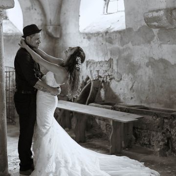 Brautpaar im Pferdestall. Bräutigam mit Hut und lässiger Kleidung, Braut in langem weißen Kleid