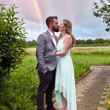 Brautpaar küsst sich unterm Regenbogen