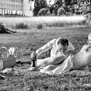 Bräutigam küsst das Strumpfband der Braut beim Picknick im Schlosspark Herrnsheim