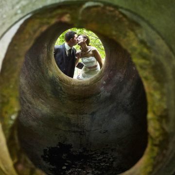 Blick auf das Brautpaar durch eine riesige Amphore mit Hochzeitkuss